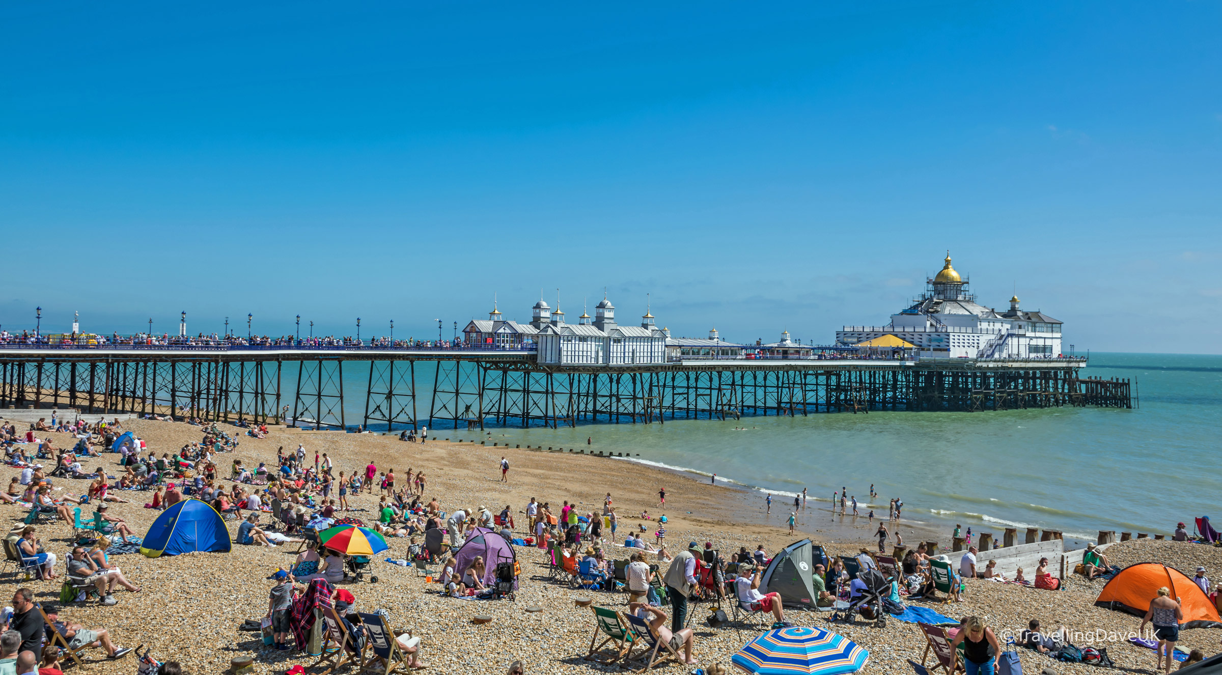 People on the beach by the pier in Eastbourne