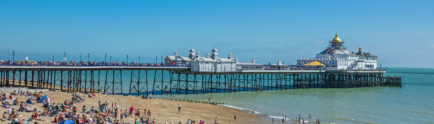 People on the beach by the pier in Eastbourne
