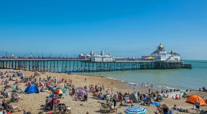 People on the beach by the pier in Eastbourne